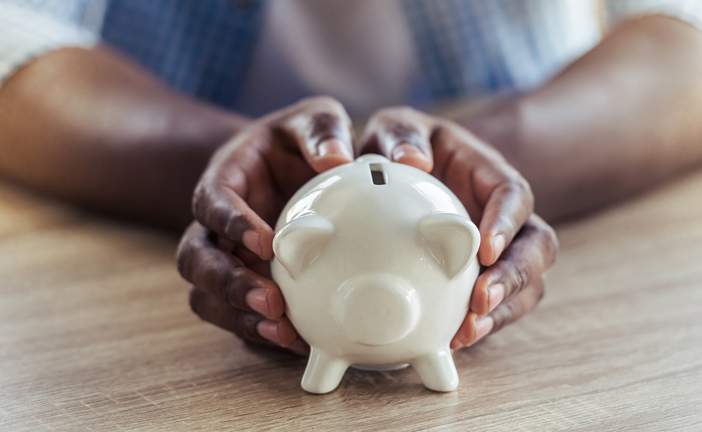 Two hands holding white piggy bank