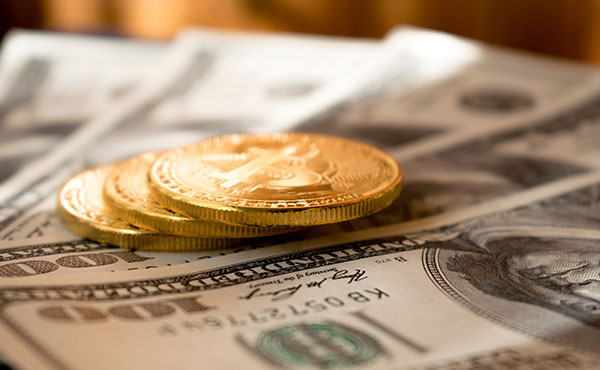 three gold coins on top of 5 US 100 dollar bills