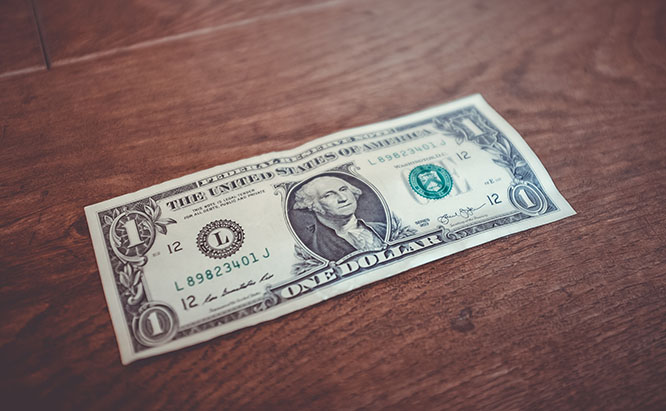 U.S. one dollar bill on top of wooden surface