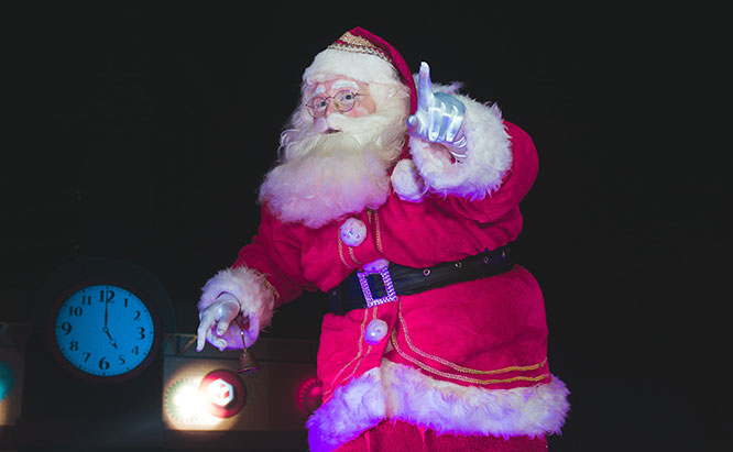 Holiday Santa Claus posing on dark stage.