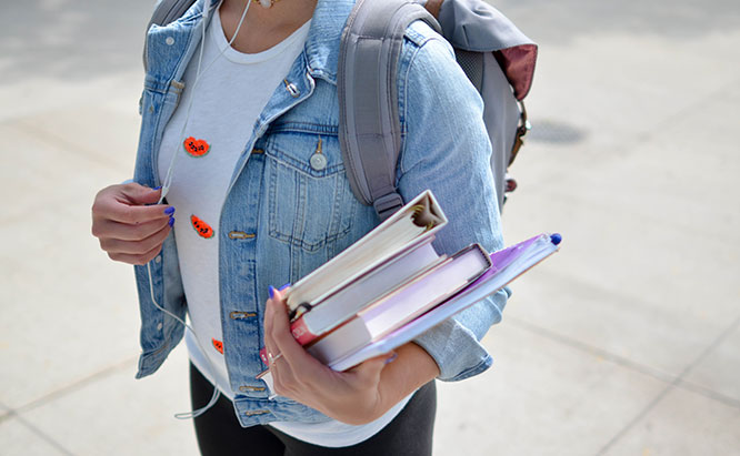 Image of young female student holding textbooks.