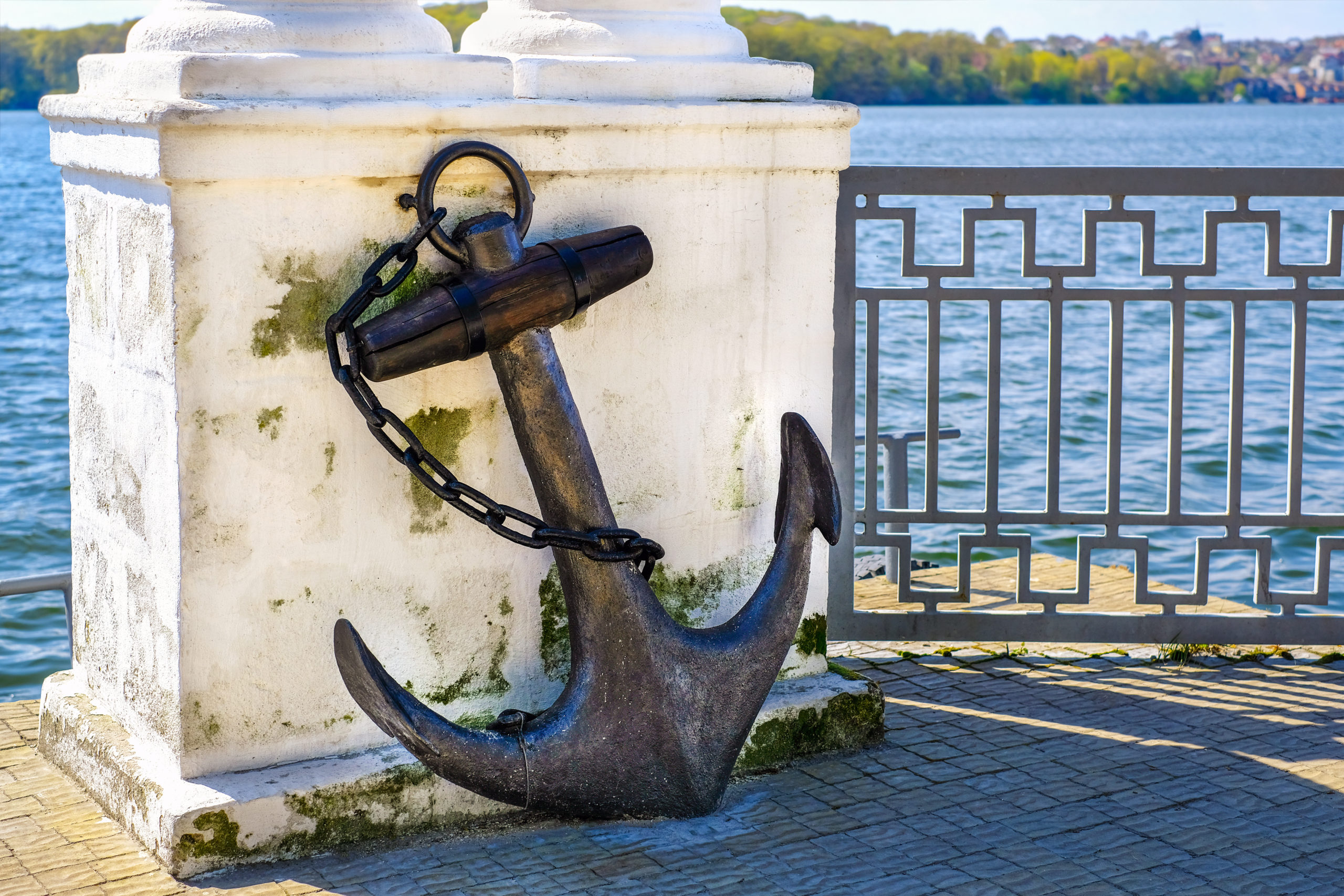 Old vintage rusty anchor in the park near lake